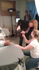 Mehrere Frauen arbeiten bei einem Fotoworkshop mit Kamera und einem Baby auf einem gepolsterten Untergrund