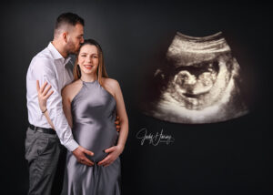 Paar mit Babybauch vor dunklem Hintergrund neben einem eingeblendeten Ultraschallbild