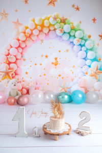 Vorbereitete Fotokulisse mit Regenbogenballons, Sternen, einer Torte und den Zahlen eins und zwei